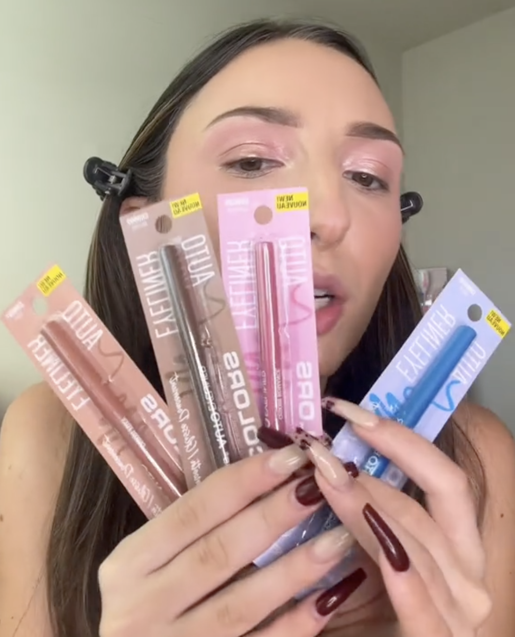 woman holding up eye liners from Dollar Tree