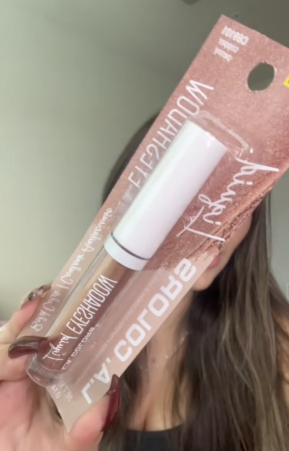 woman holding up liquid eyeshadow from Dollar Tree
