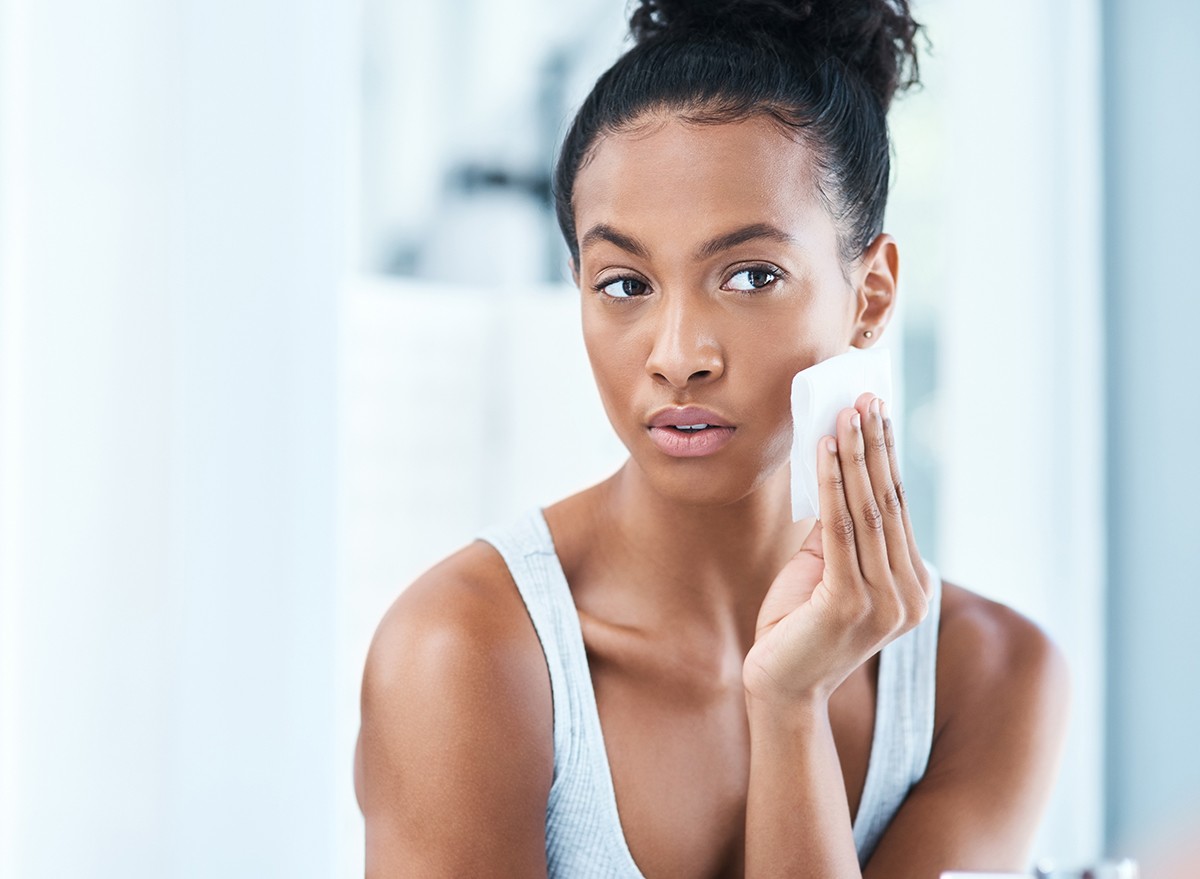 Woman using a face wipe looking in the mirror
