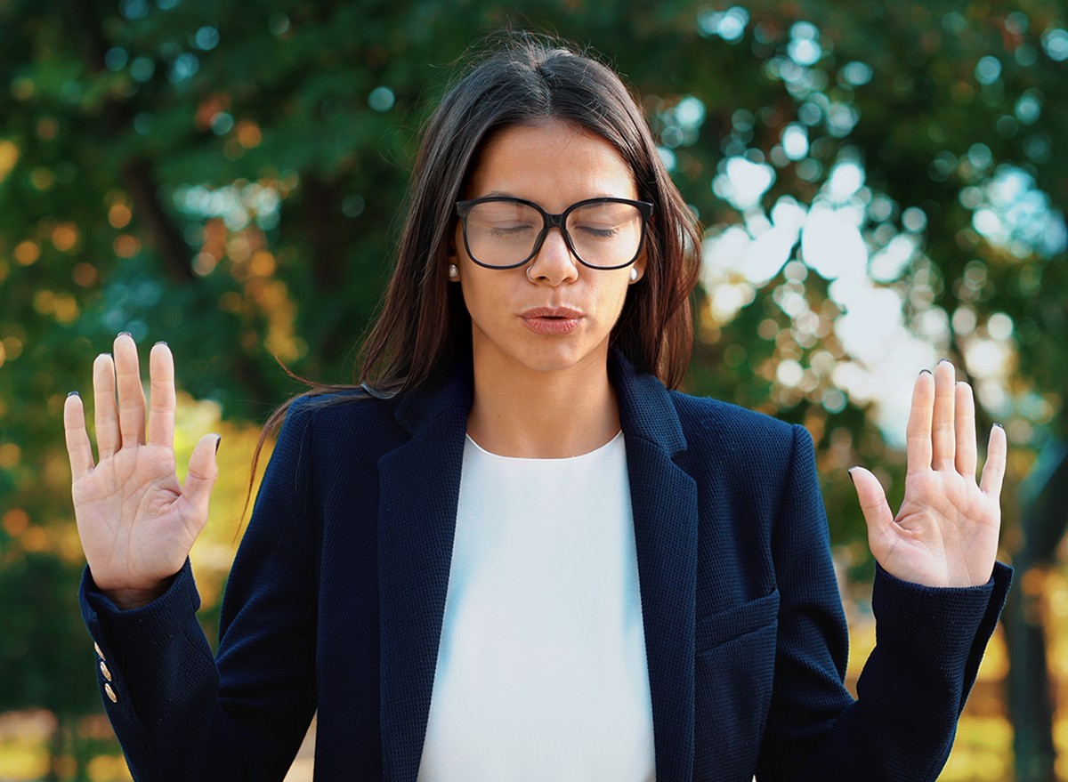 A woman experiencing stress puts her hands up and breathes deeply