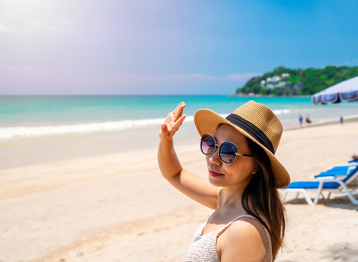 Woman on the beach shields her face from UV rays