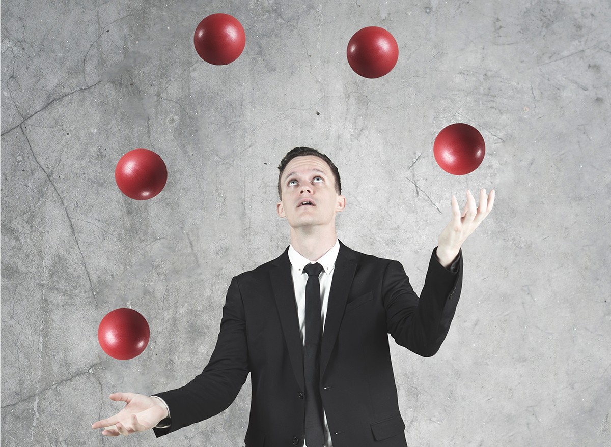 A businessman juggles five balls in the air