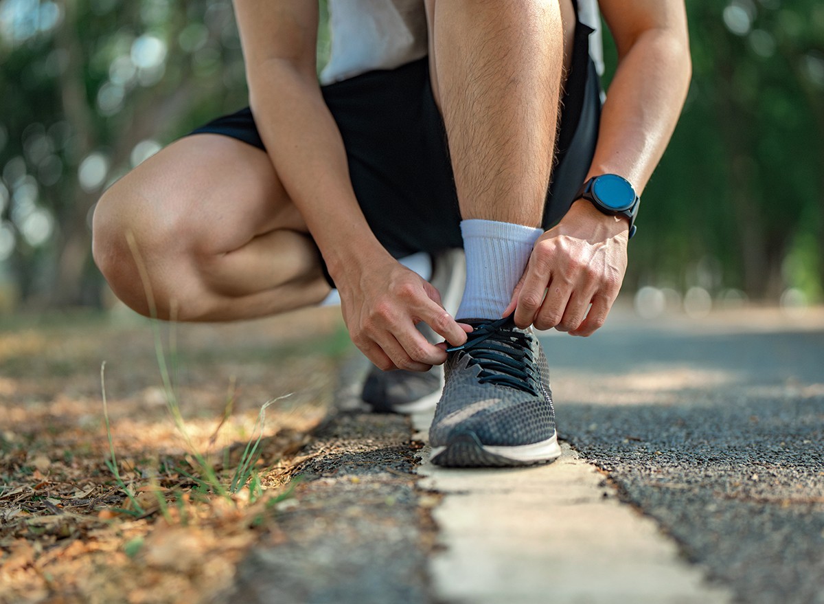 A man crouches down to tie his shoe laces