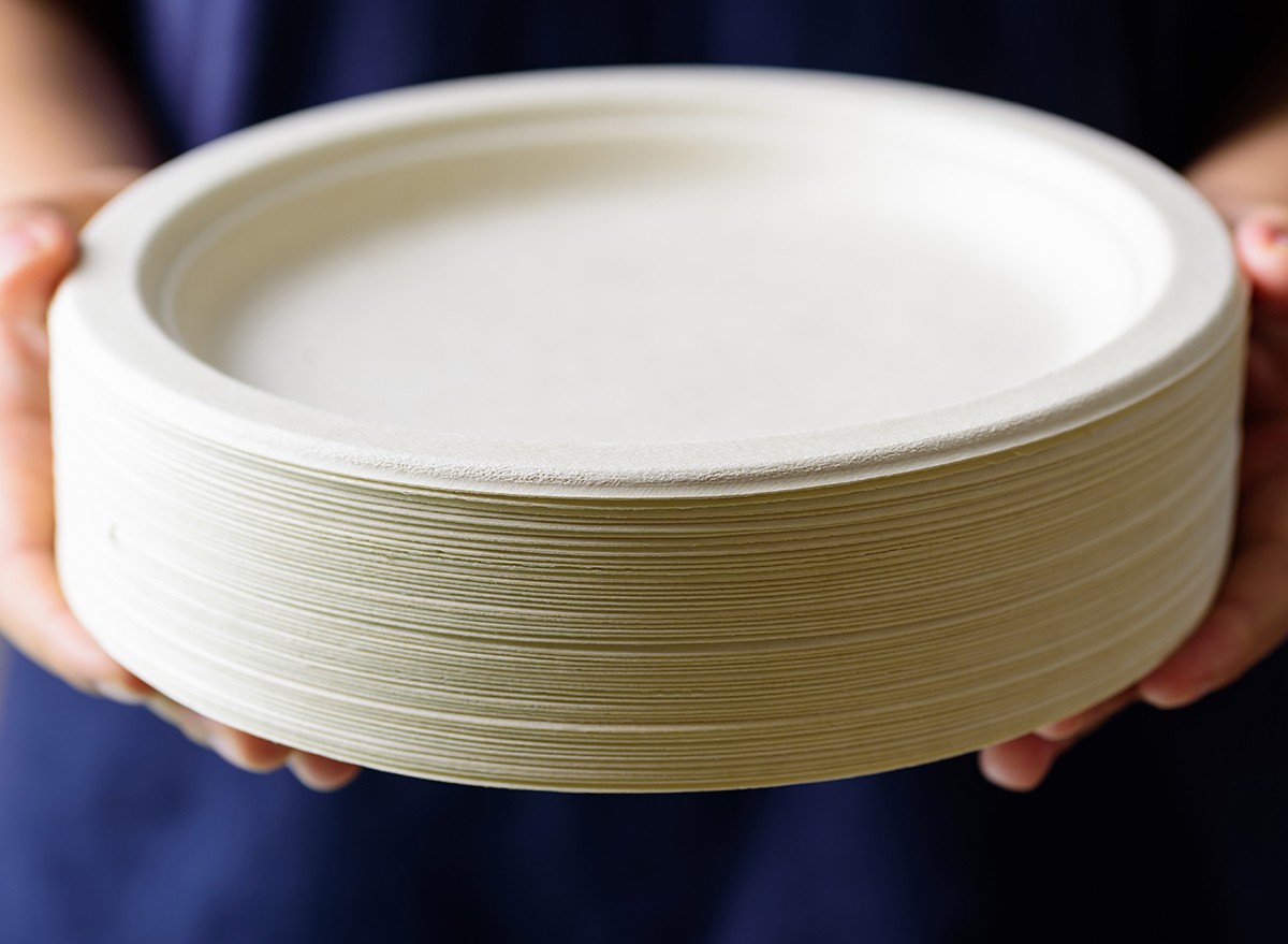 Hands holding a stack of paper plates