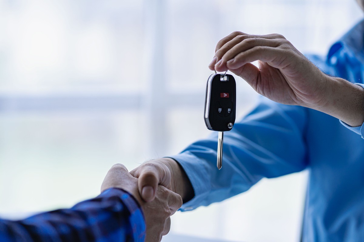 Car salesman gives keys to buyer of a new car