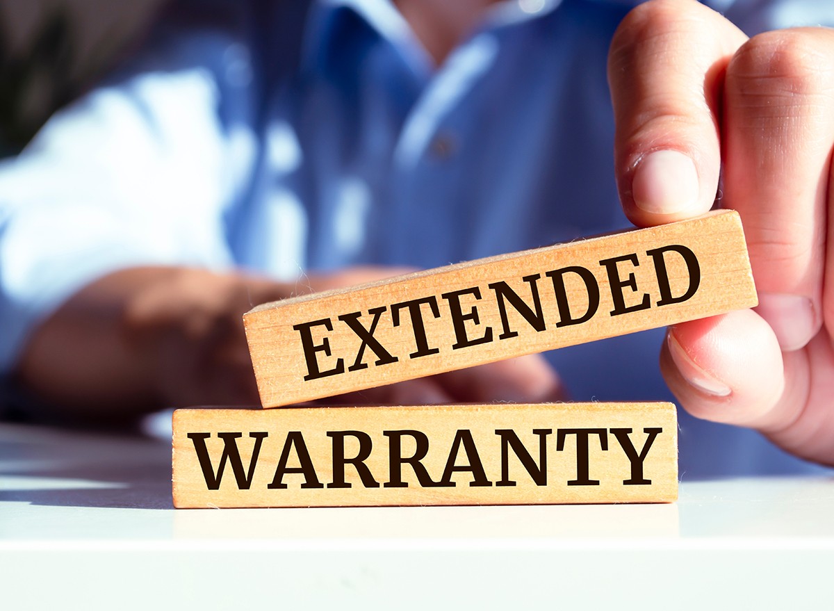 A man's hand holding an 'extended warranty' sign