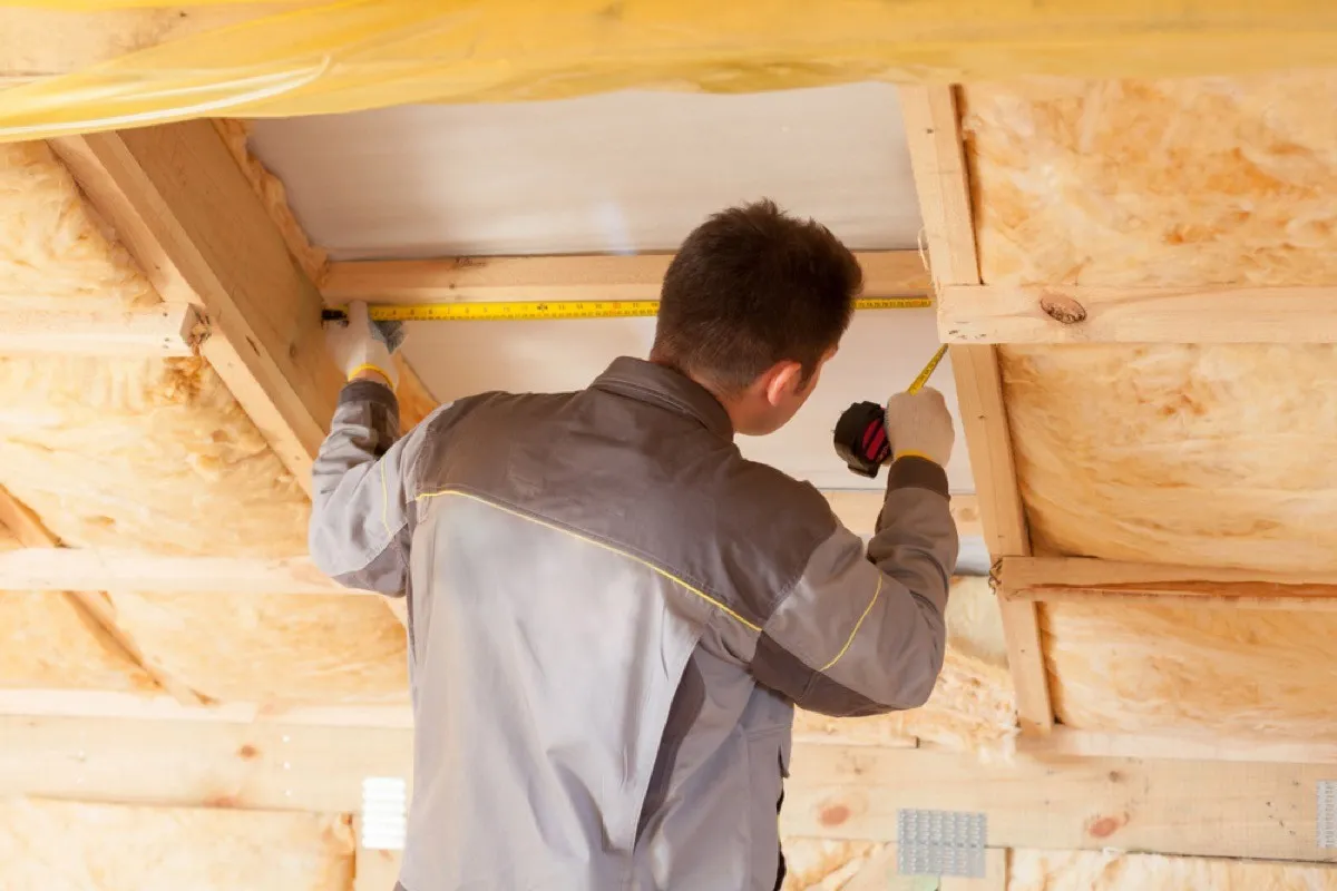 A man installs insulation in attic