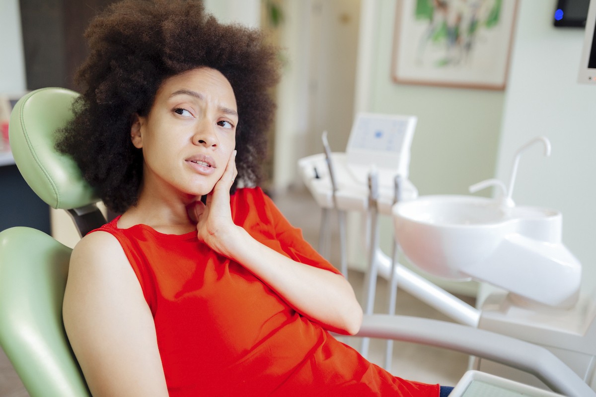 Woman sitting in a dentist's chair, holding her cheek