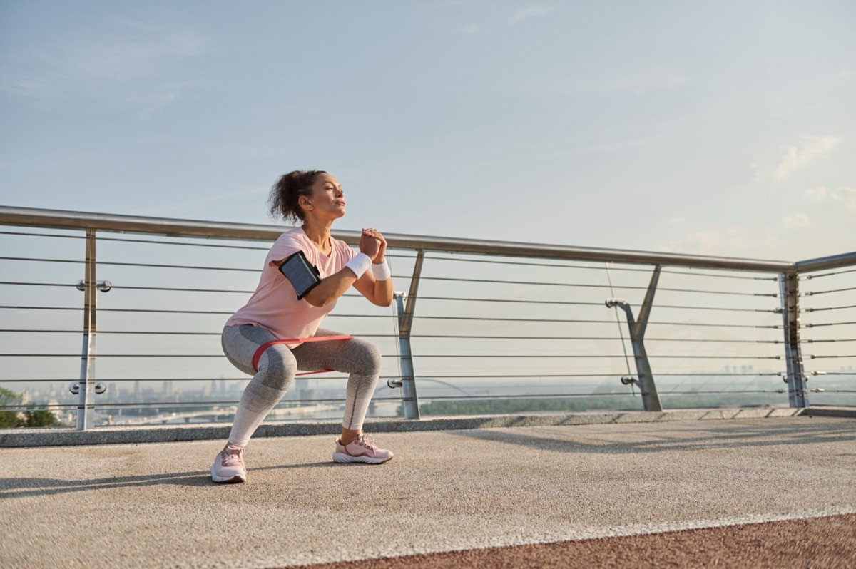 woman doing squats in the middle of her walk