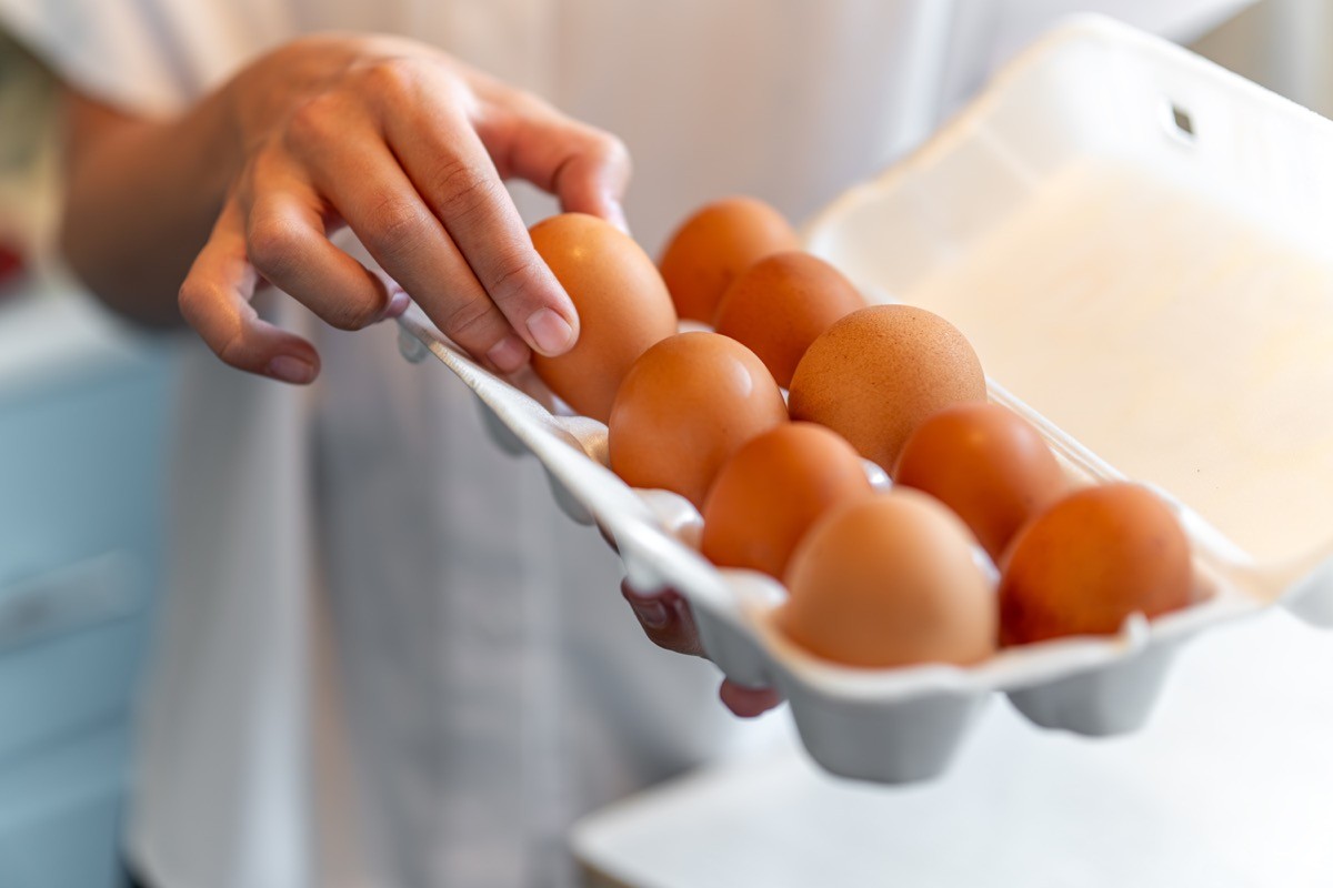 women with holding a cardboard egg box full of her eggs.