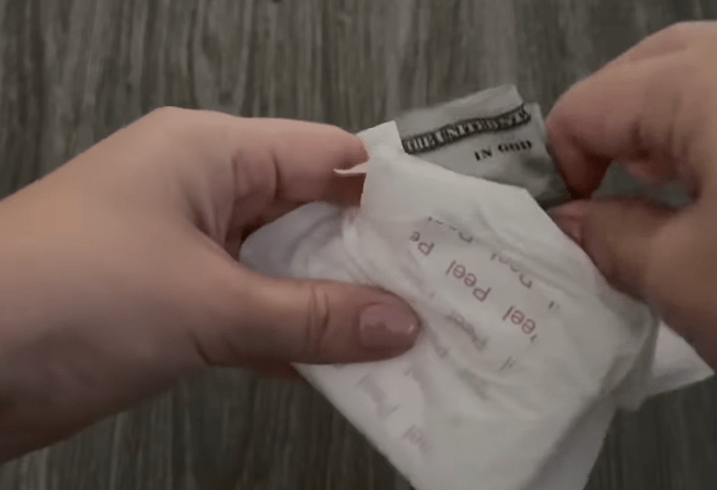 closeup of a person putting cash in a feminine pad