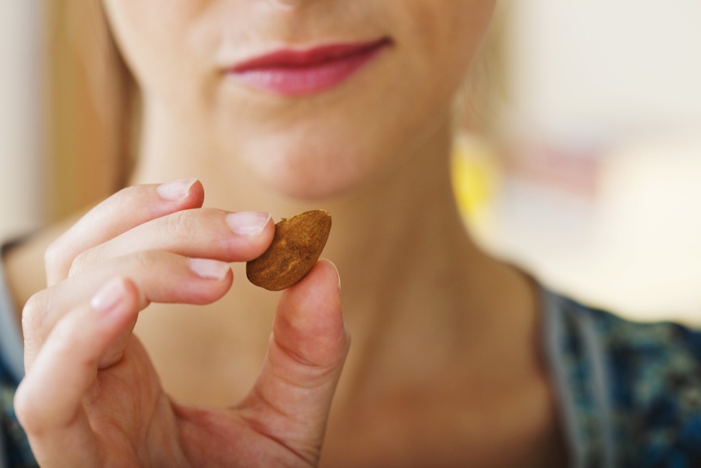 Woman eating an almond, high in vitamin E