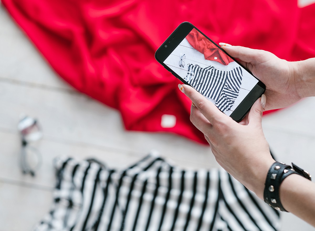 A woman takes a photo of clothing on the floor