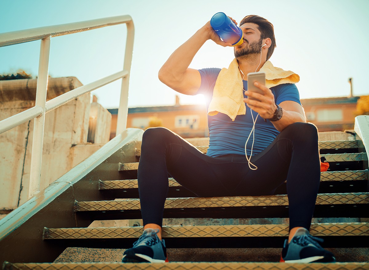 A man sits and drinks water during a workout