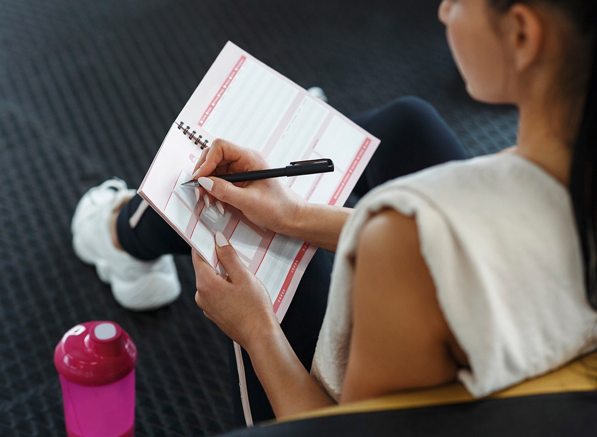 A woman planning workouts in a notebook.