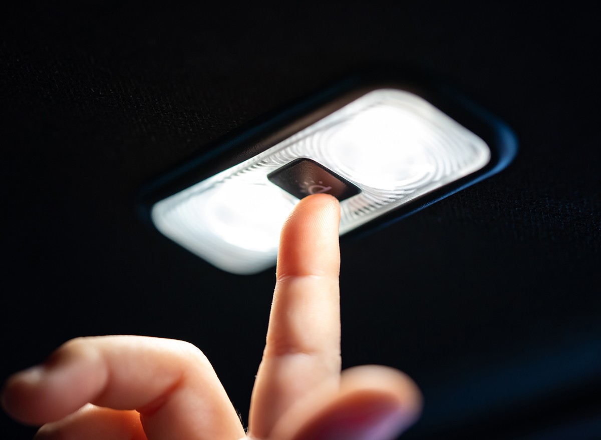 A child's finger pressing the center light in a car