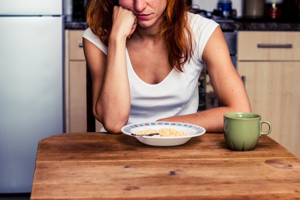 Woman looking at a bowl of food on a wooden table