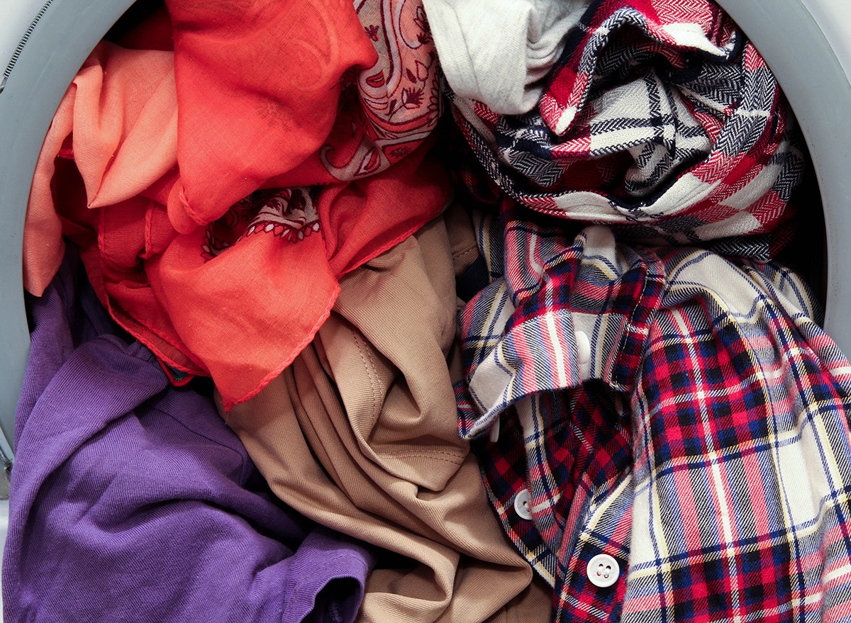 Clothes spilling out of an overloaded washing machine