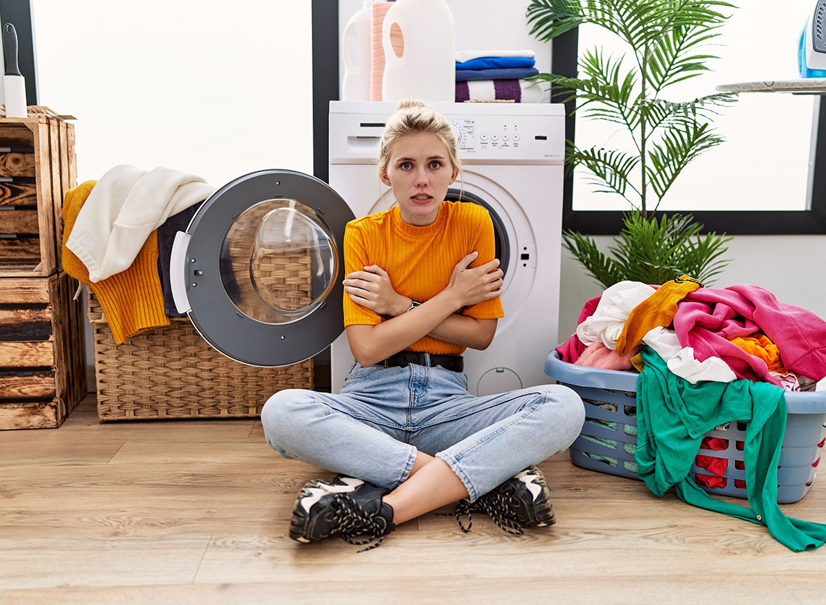 A woman sitting on the floor, doing laundry, feeling the cold in winter