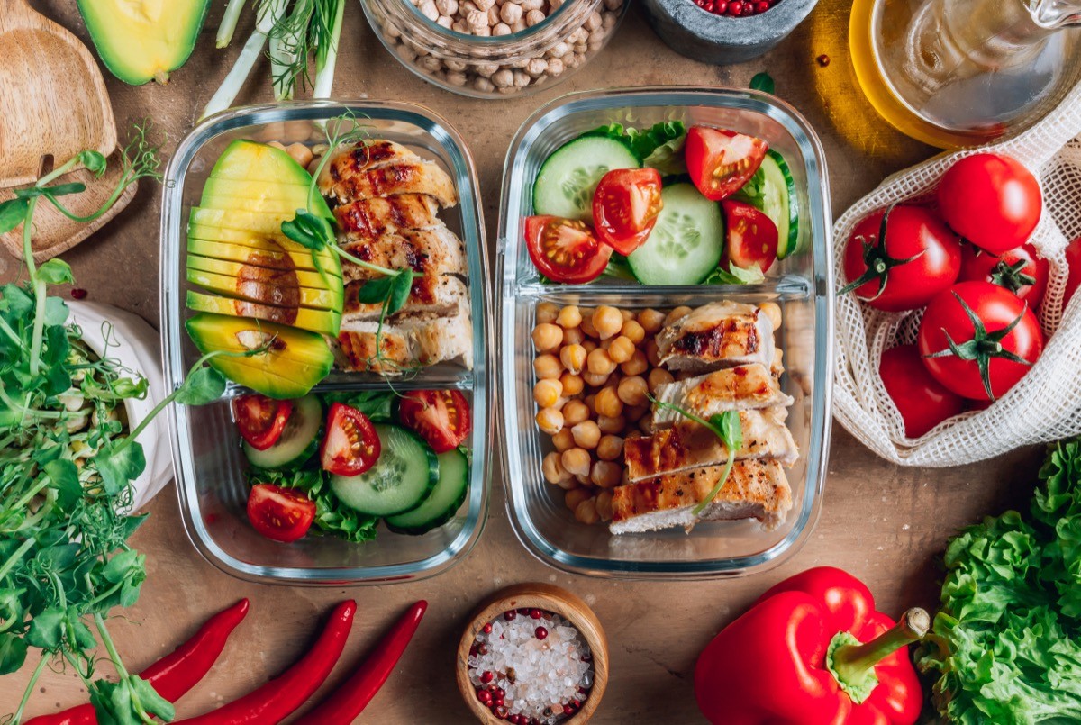 Healthy meal prep containers with chickpeas, chicken, tomatoes, cucumbers and avocados