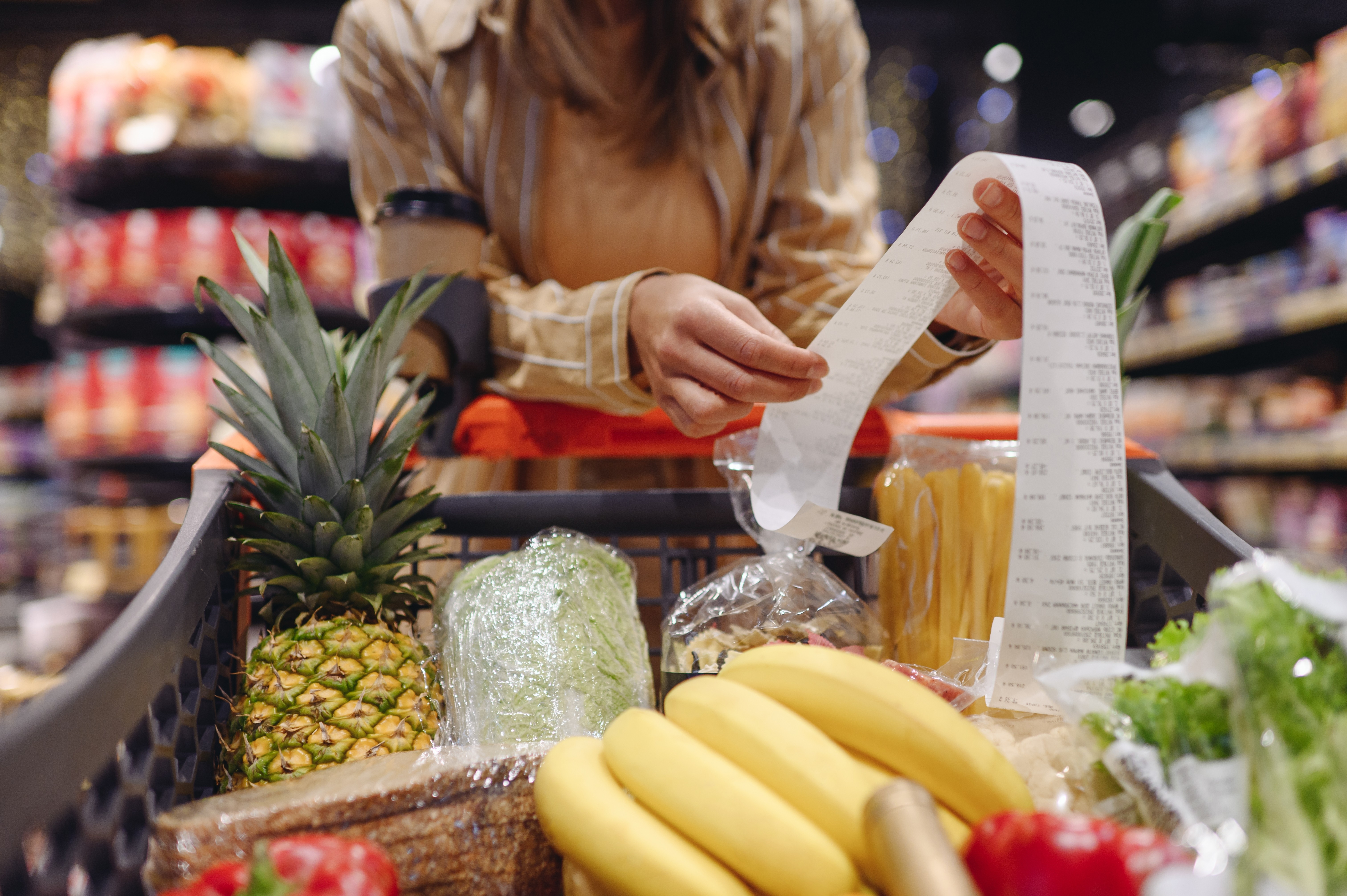 A woman looks at her grocery receipt leaving the store