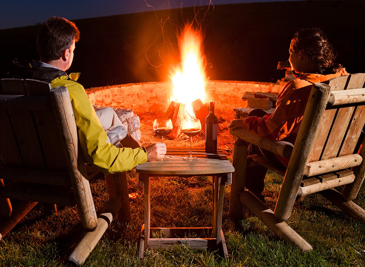 Couple sitting around a fire drinking wine