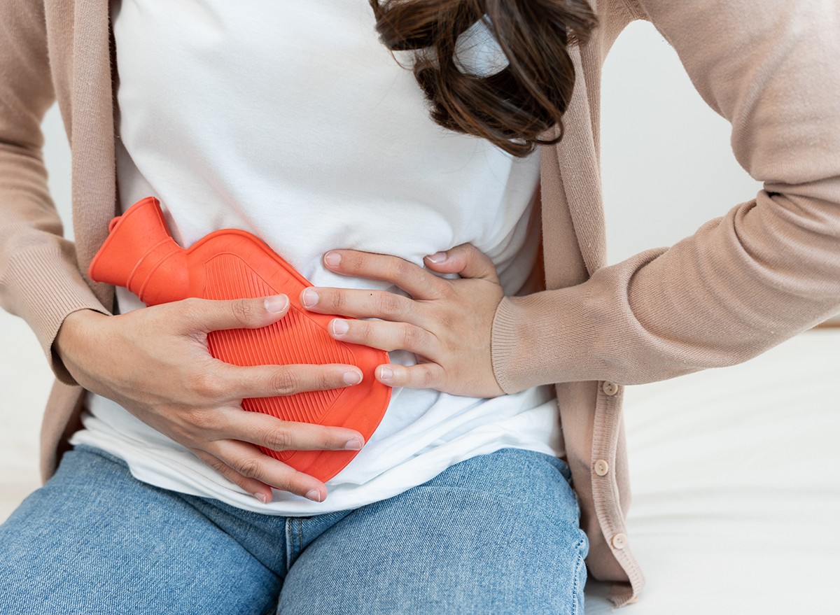 A woman with menstrual cramps uses a hot water bottle