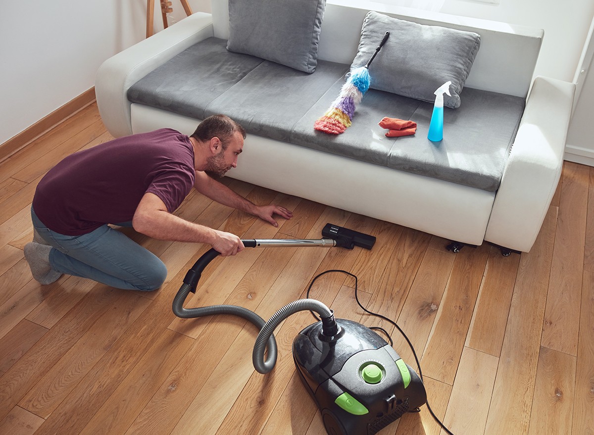 A man vacuuming under a couch