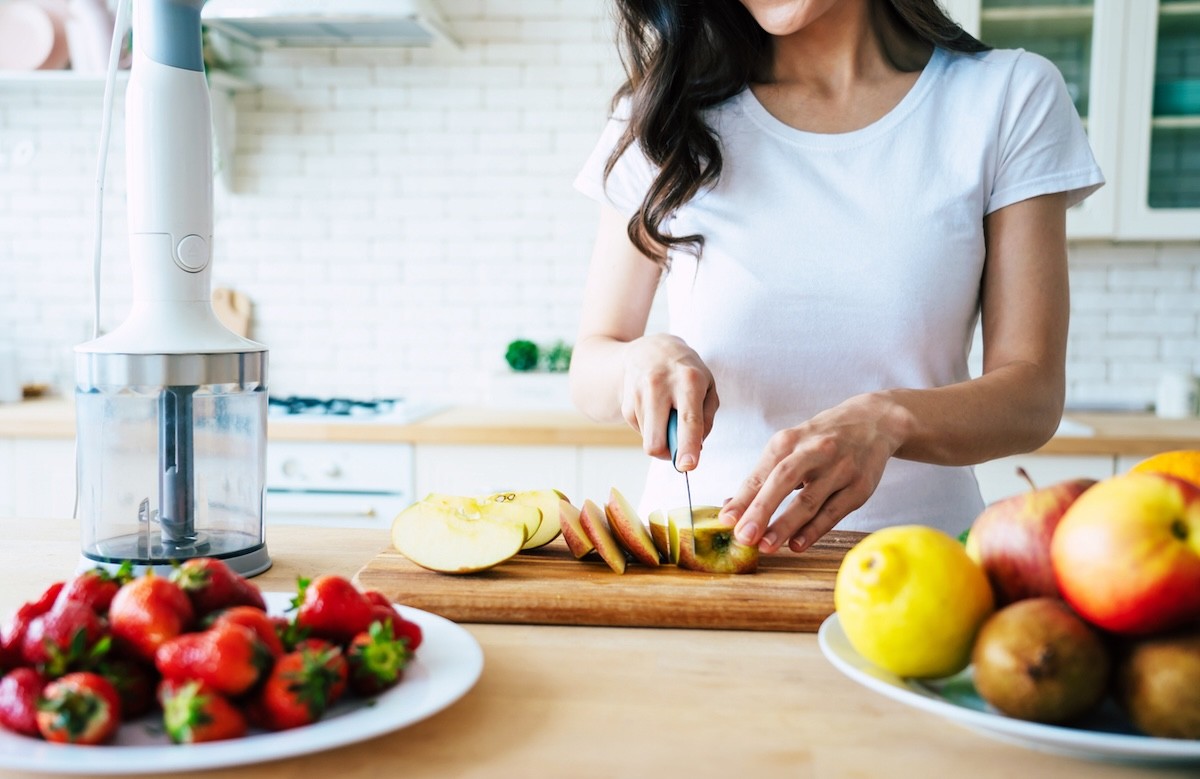 Woman cutting up an apple on a cutting board on her kitchen counter