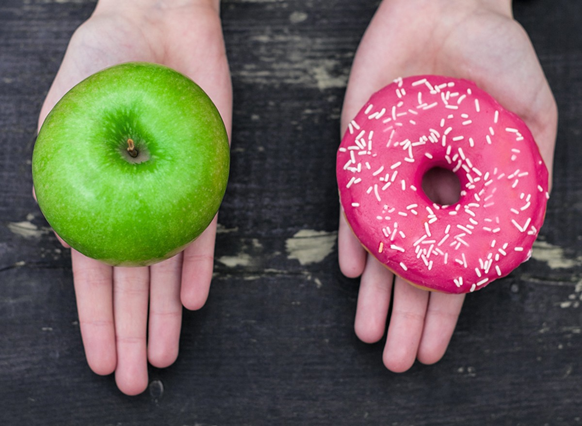 An apple in one hand and a donut in the other