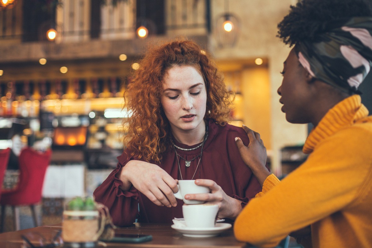 A young woman is talking with a female friend in a cafe