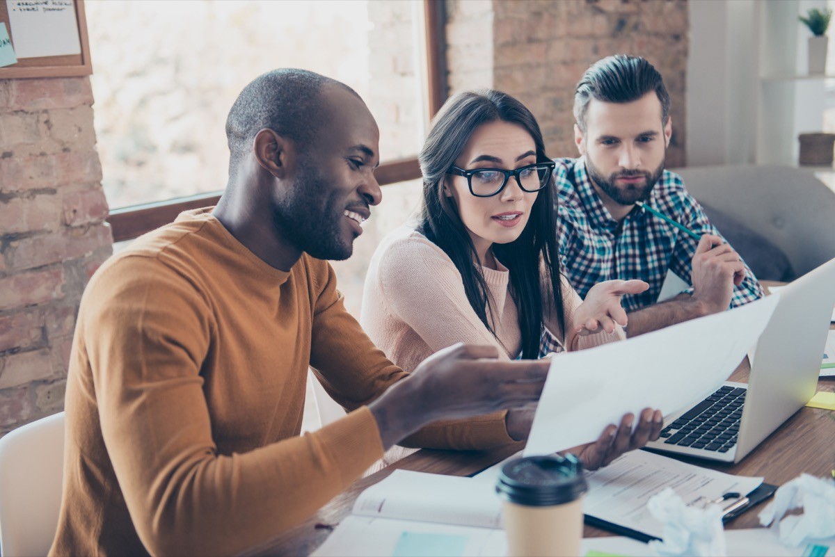 Three coworkers in an office working and discussing a project