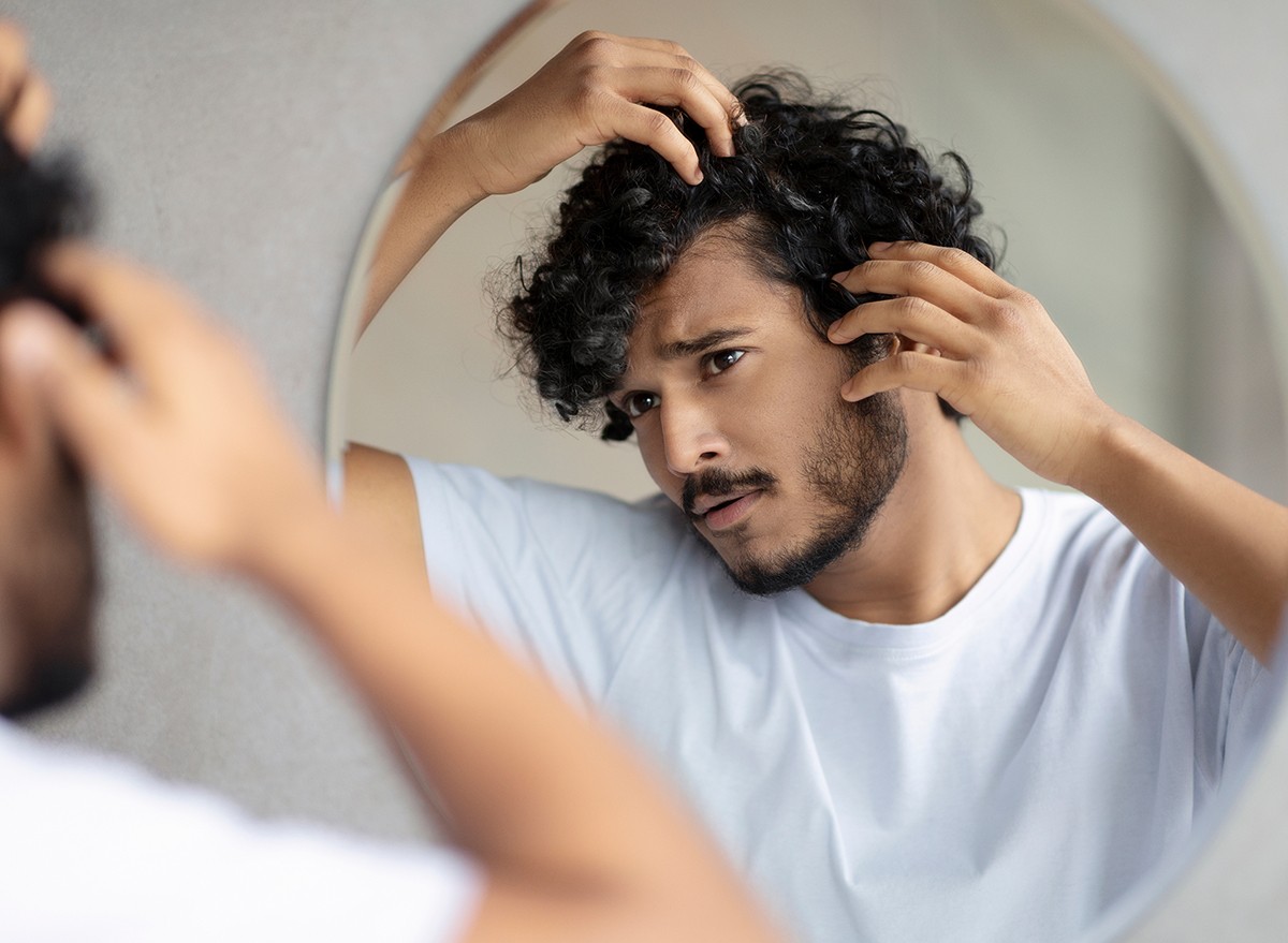 A man with dandruff looks in the mirror