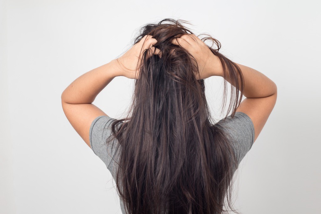 A woman with dry hair runs her hands through her hair