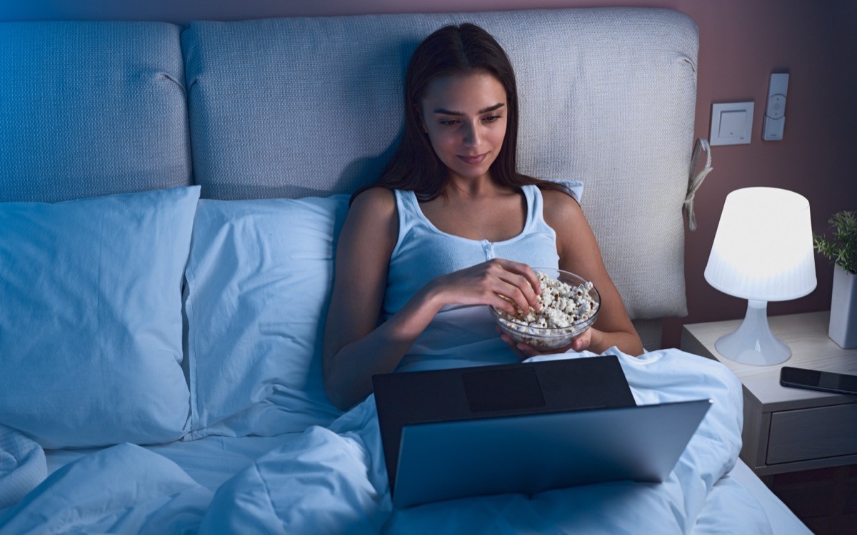 Woman Eating Popcorn in Bed late at night