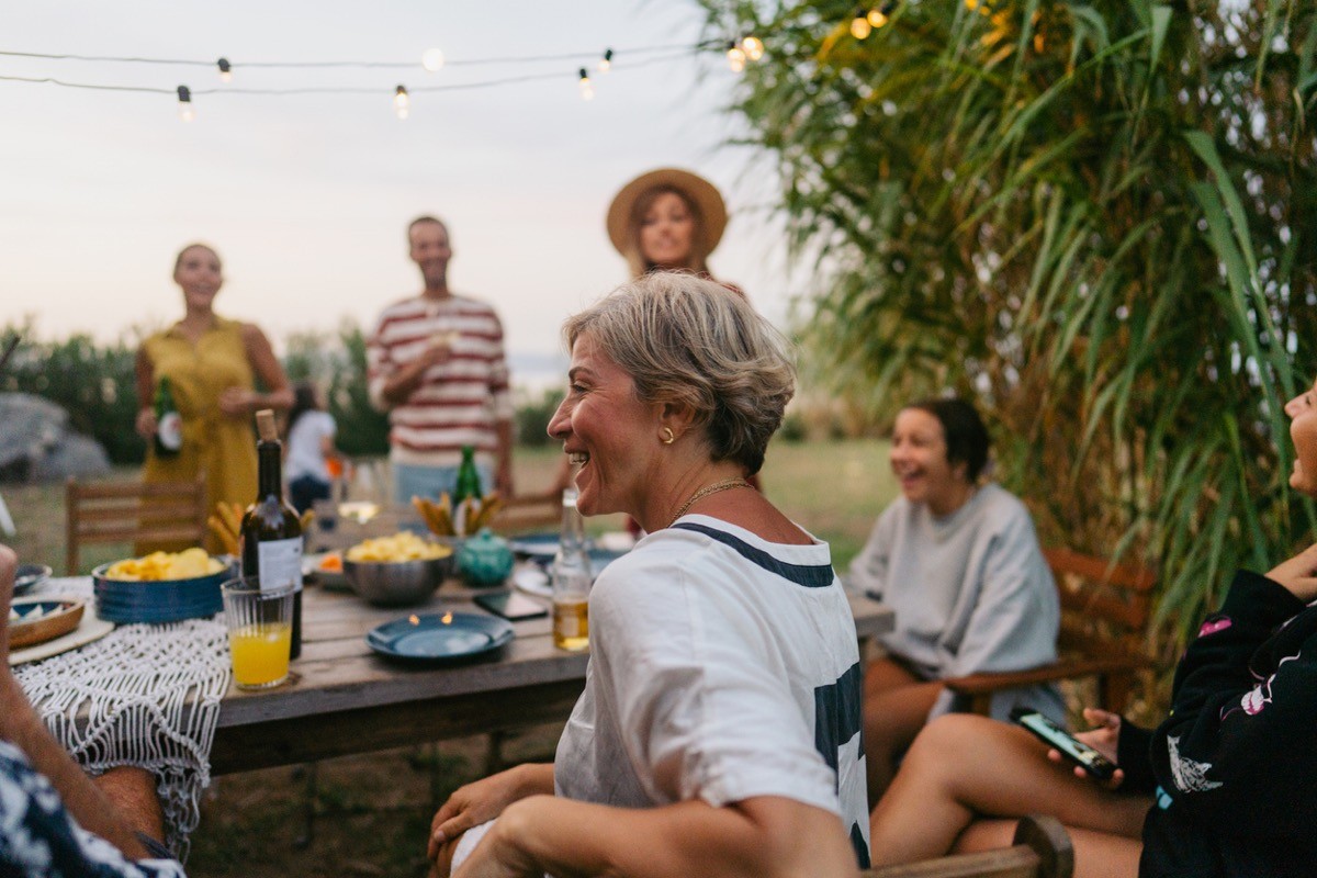 Photo of a woman enjoying the outdoor dinner party with her family and friends