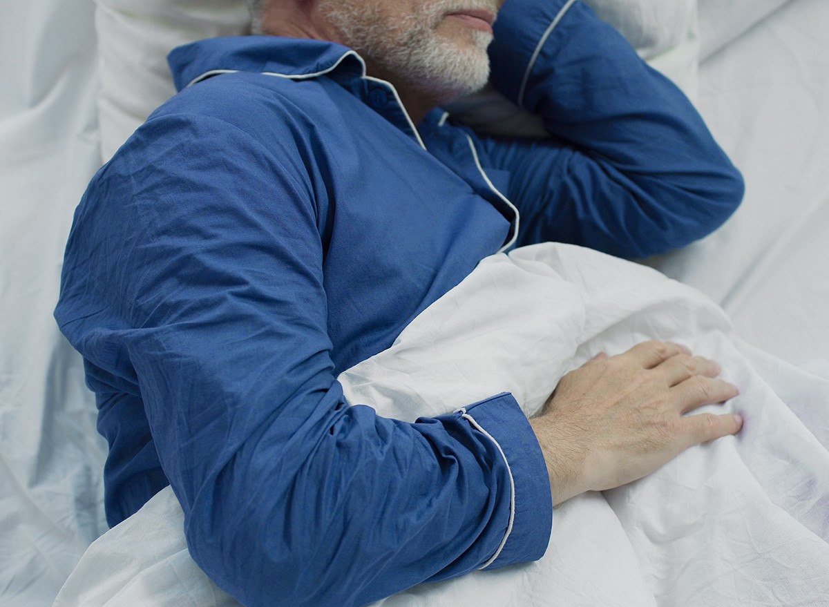 A man sleeping in bed under a comforter
