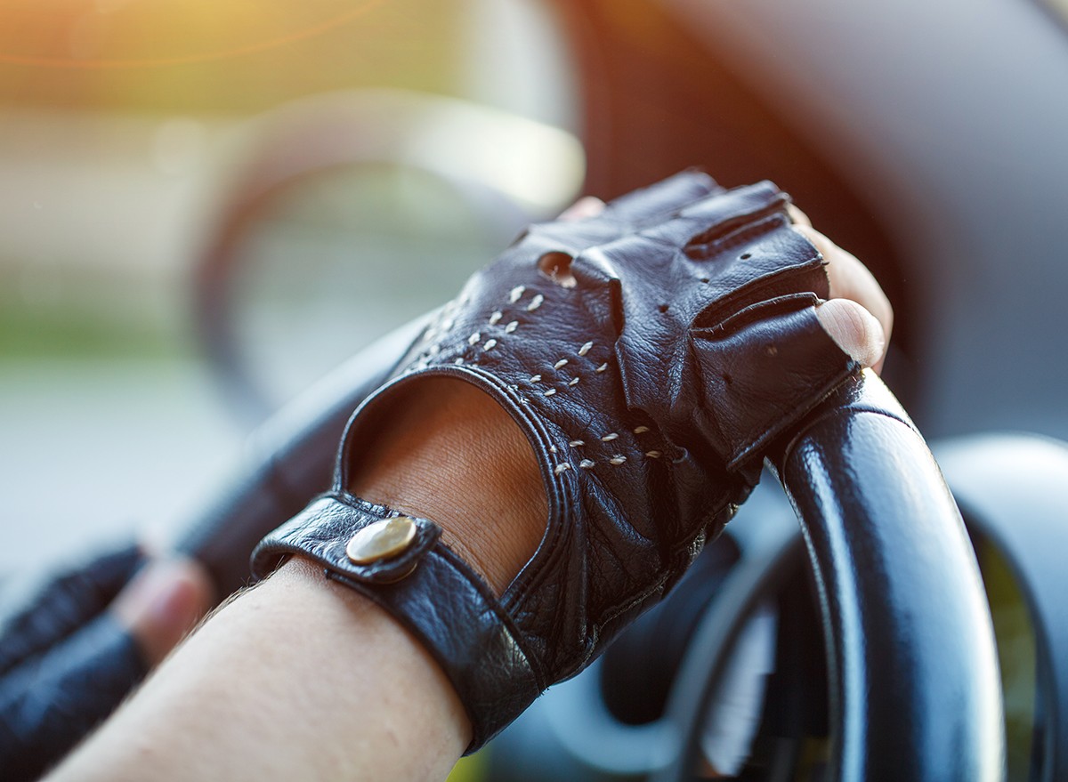 A driver wearing gloves with hands on the steering wheel
