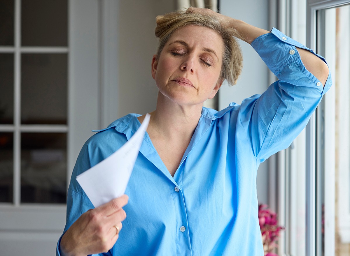 A woman having a hot flash fanning herself