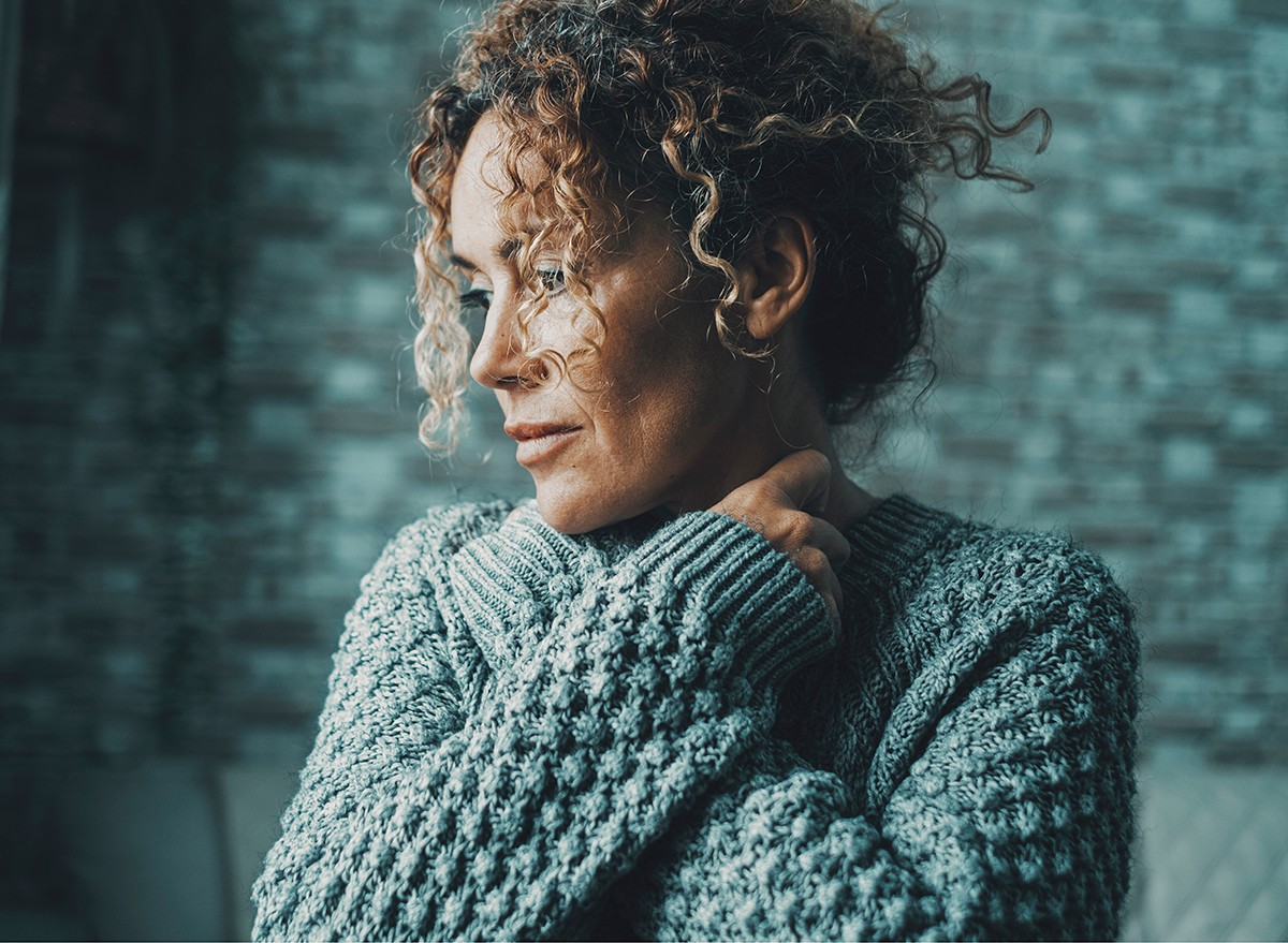 A woman wearing a sweater has chills following a hot flash