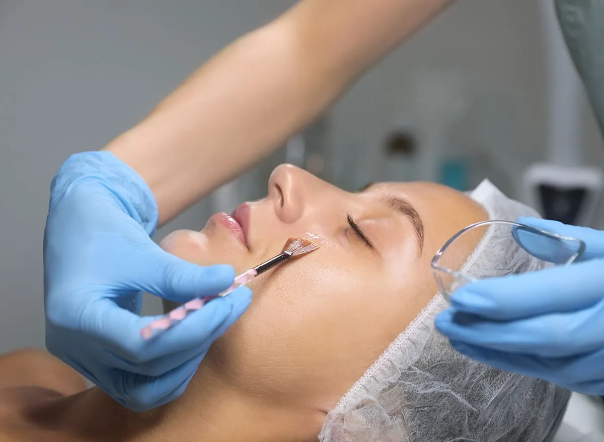 Cosmetologist applying chemical peel product on client's face
