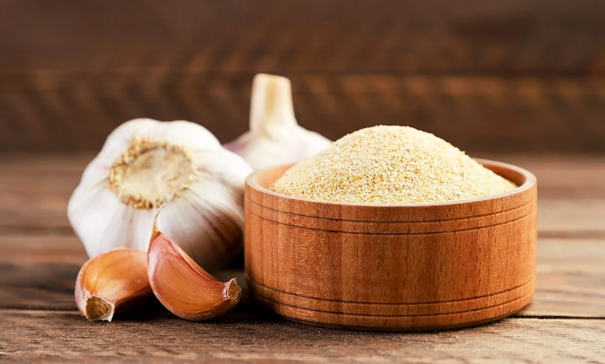 garlic bulbs and a wooden bowl of garlic powder