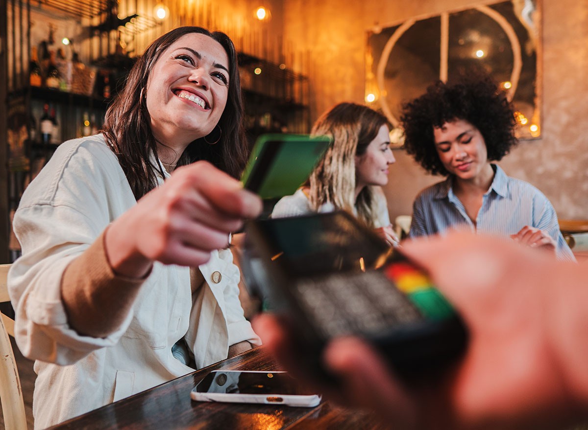 A happy woman paying the check in a restaurant