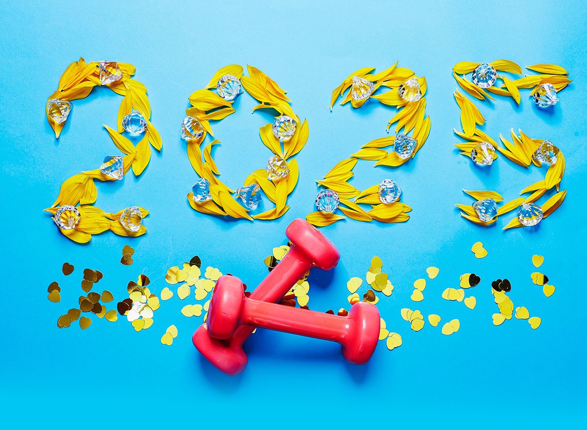 2025 written in flower petals and confetti with a pair of hand weights in the foreground