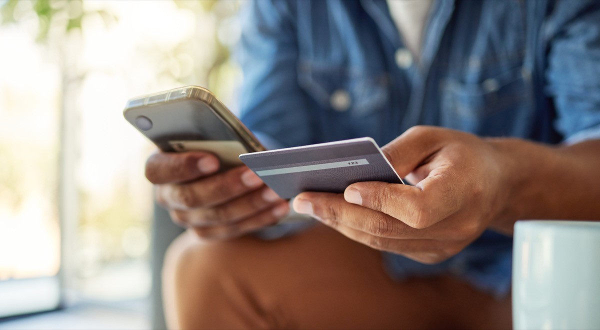Closeup of a man holding a credit card and looking at his phone