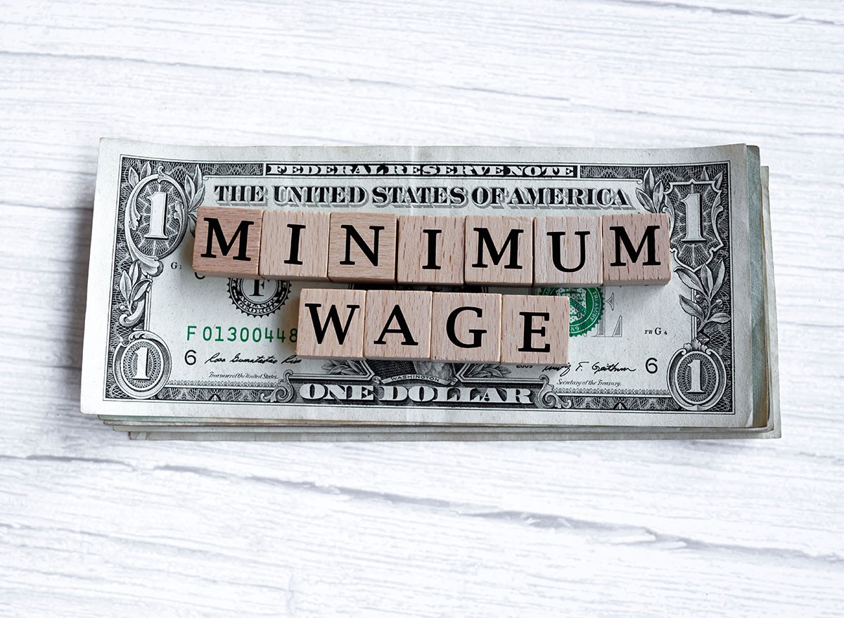 Minimum wage word written on wood block with American Dollar-bills