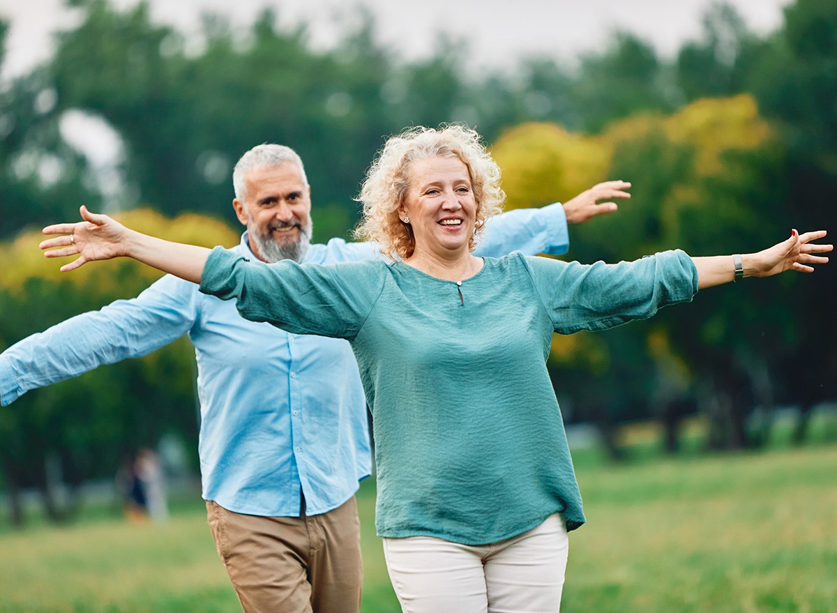 A happy active middle-aged couple doing balancing exercises in the park 