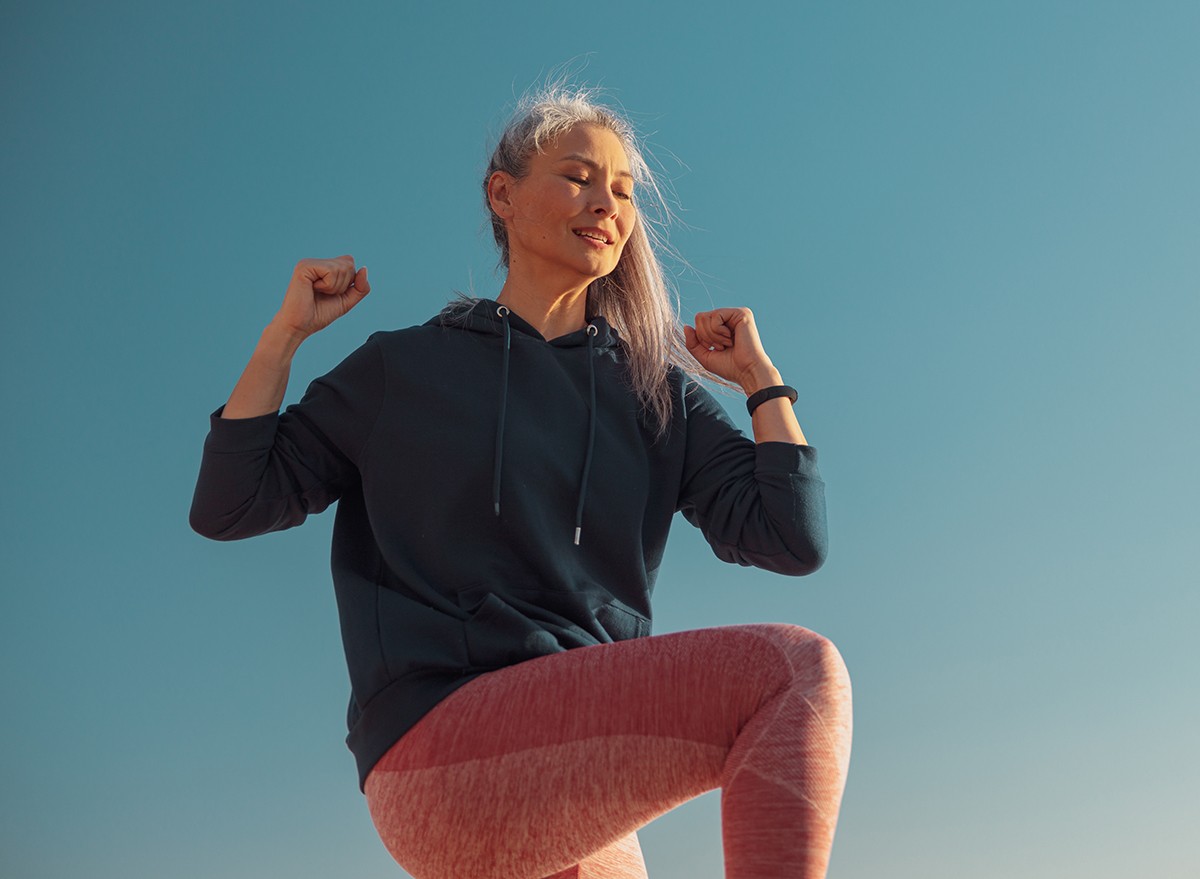 A woman stands on one foot and lifts her knee up 