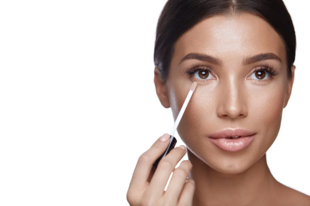 woman applying concealer makeup