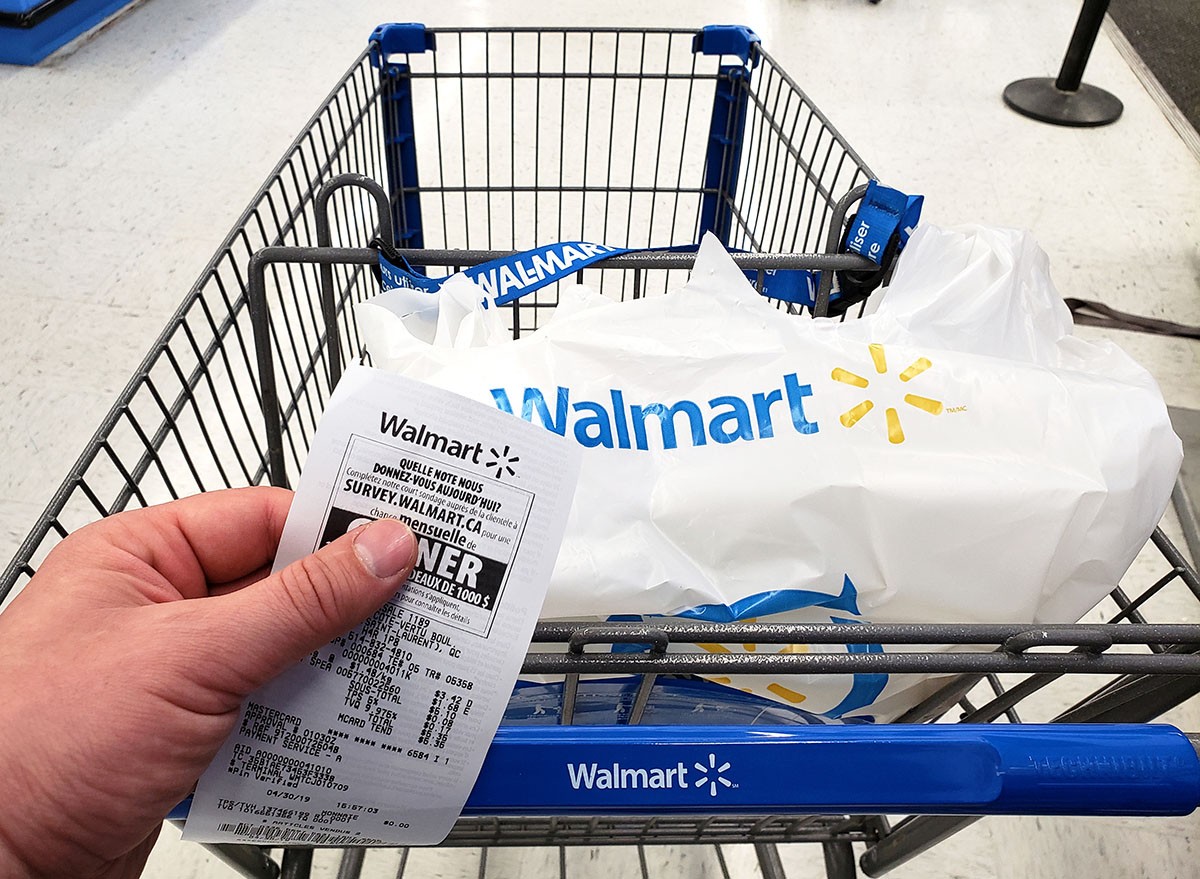 A walmart customer pushing a cart holding a receipt